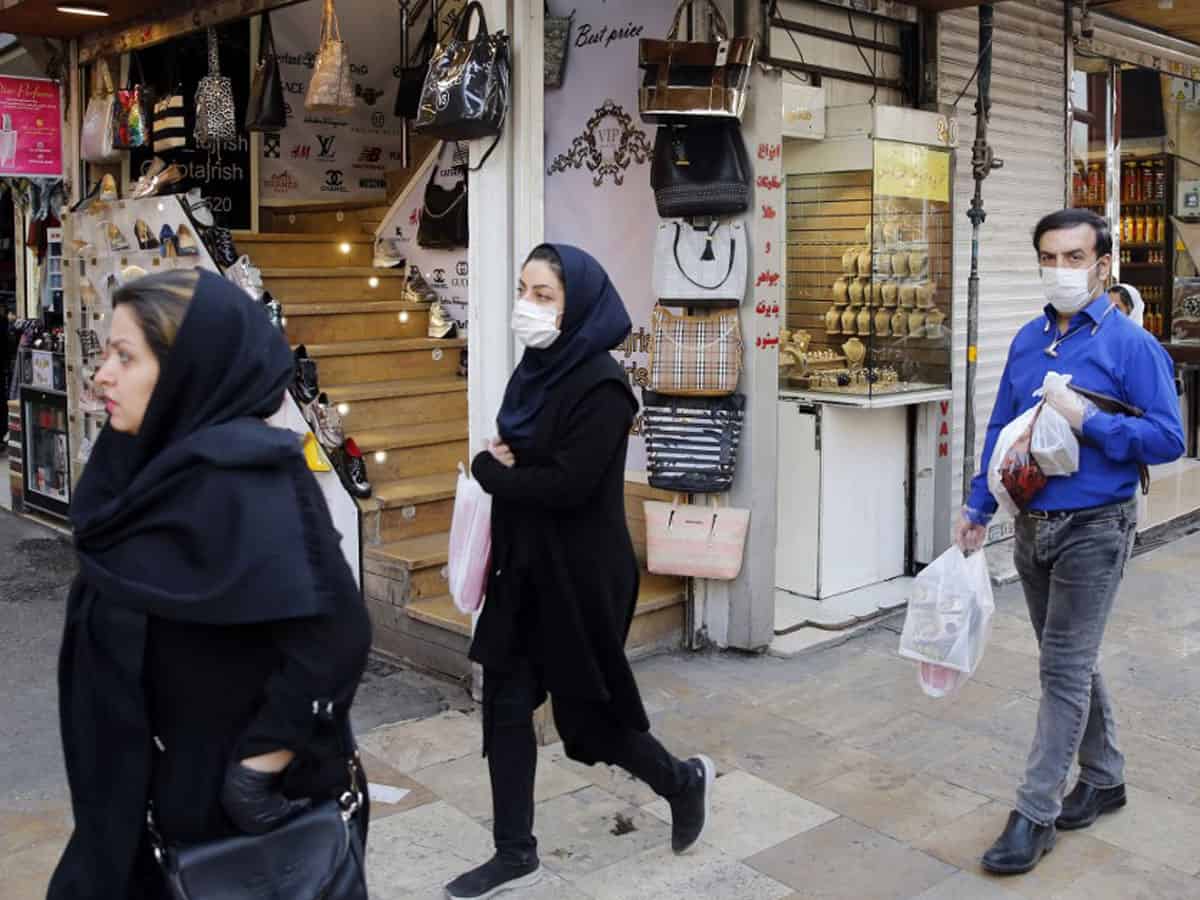 People, some wearing protective face masks, walk past shops along outside the Tajrish Bazaar in Iran's capital Tehran on March 12, 2020. Photo: AFP