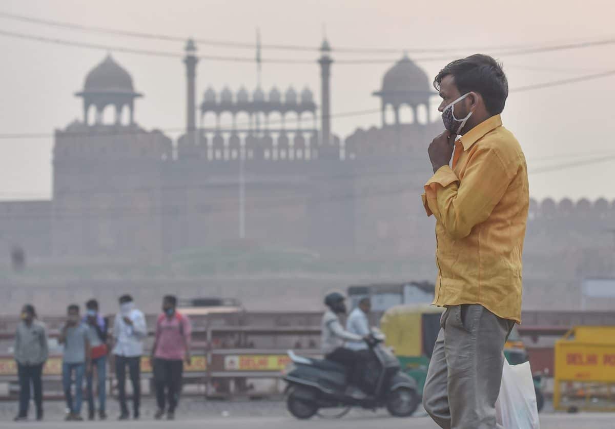 New Delhi: A man walks along a road in the backdrop the Red Fort amid hazy weather conditions, in New Delhi. (PTI Photo/Manvender Vashist