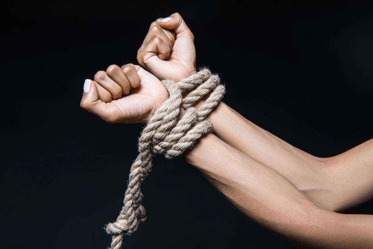 cropped shot of female hands bound with rope isolated on black